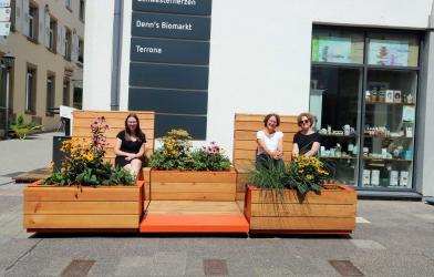 Nathalie Dörl-Heby, Alexandra Schmidt und Lena Fauth sitzen auf bepflanzten Sitzmöbeln vor der Weißhofer Galerie